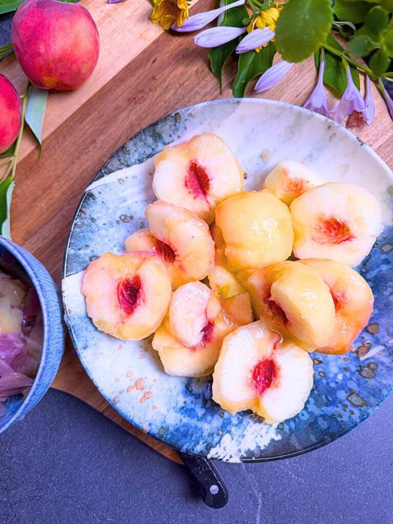Peaches cut in half in a blue and white bowl.