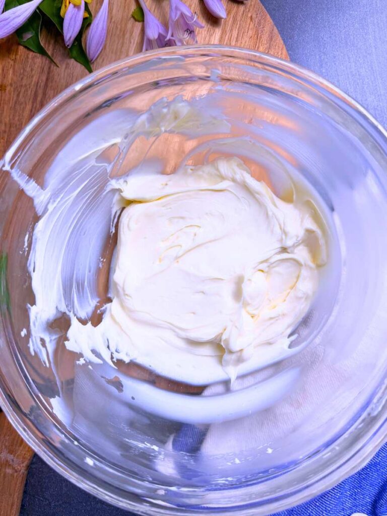 A glass bowl with a cream cheese mixture inside.