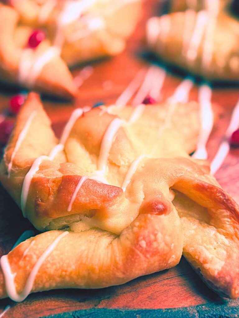A sourdough cheese danish with a vanilla icing drizzle on top.
