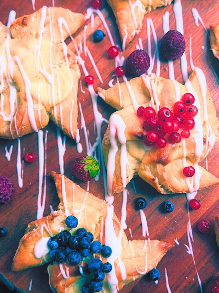 An overhead view of three sourdough cheese danishes with berries on top.
