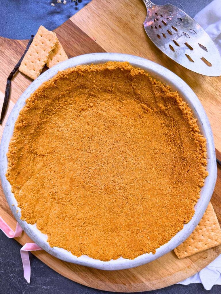 A graham cracker crust in a metal pie plate.