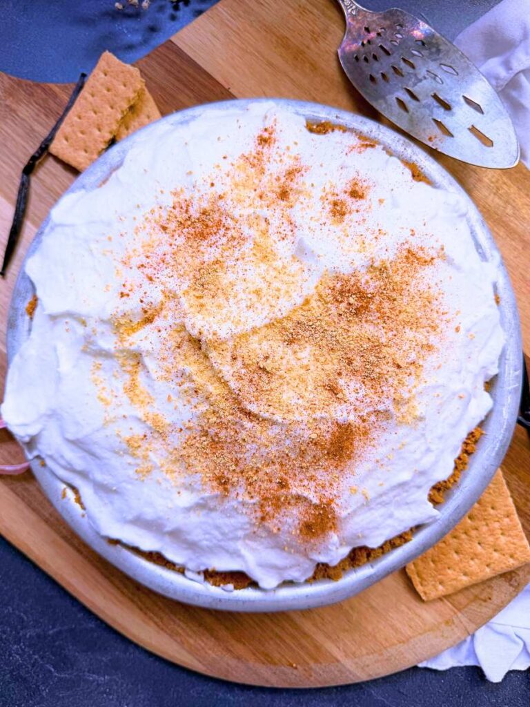 A pie with a meringue top and graham cracker crumbs and cinnamon dusted on top.