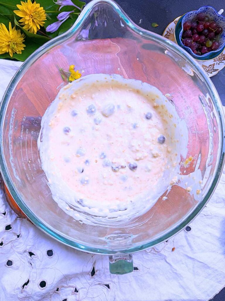 A large glass bowl with gooseberry muffin batter inside.