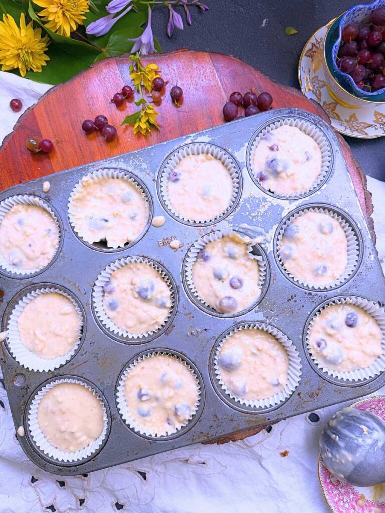 A lined muffin tin with filled with gooseberry muffin batter.