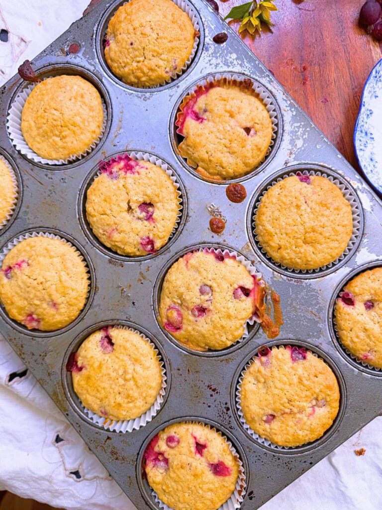 Baked gooseberry muffins in a lined muffin tin.