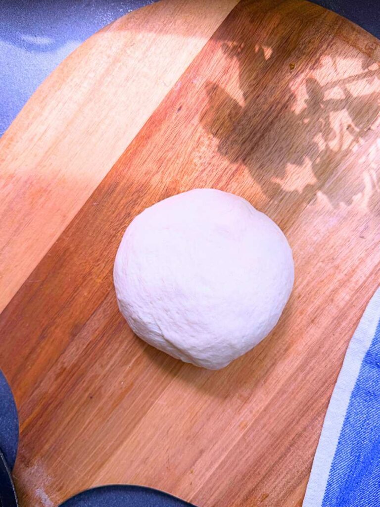A dough ball on a wooden board.