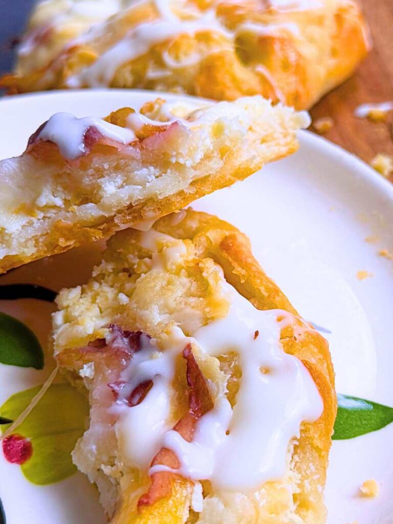 A peach Danish on a white plate split in half.