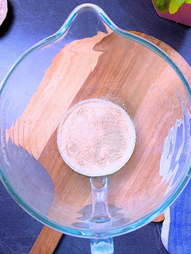 A glass bowl with milk and dry yeast inside.
