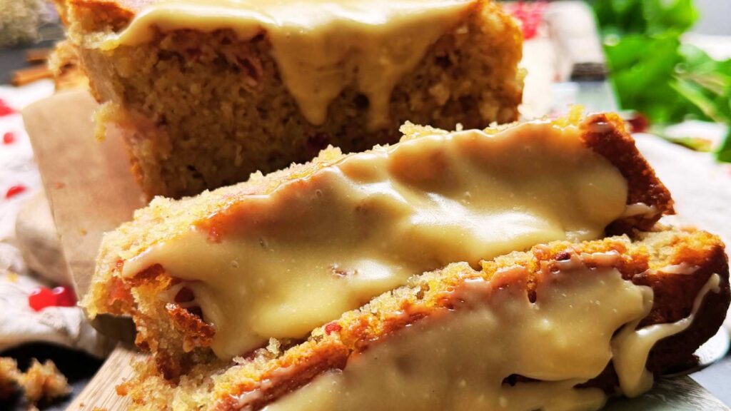 A sliced red current loaf cake with brown sugar icing on top.