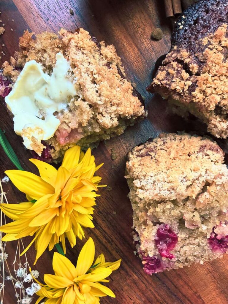An overhead view of 3 slices of gooseberry coffee cake. There are yellow flowers beside.