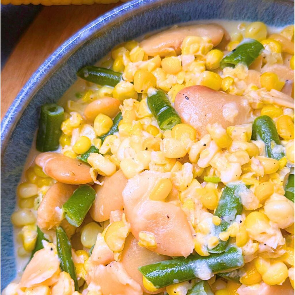 A blue bowl filled with corn and bean succotash.