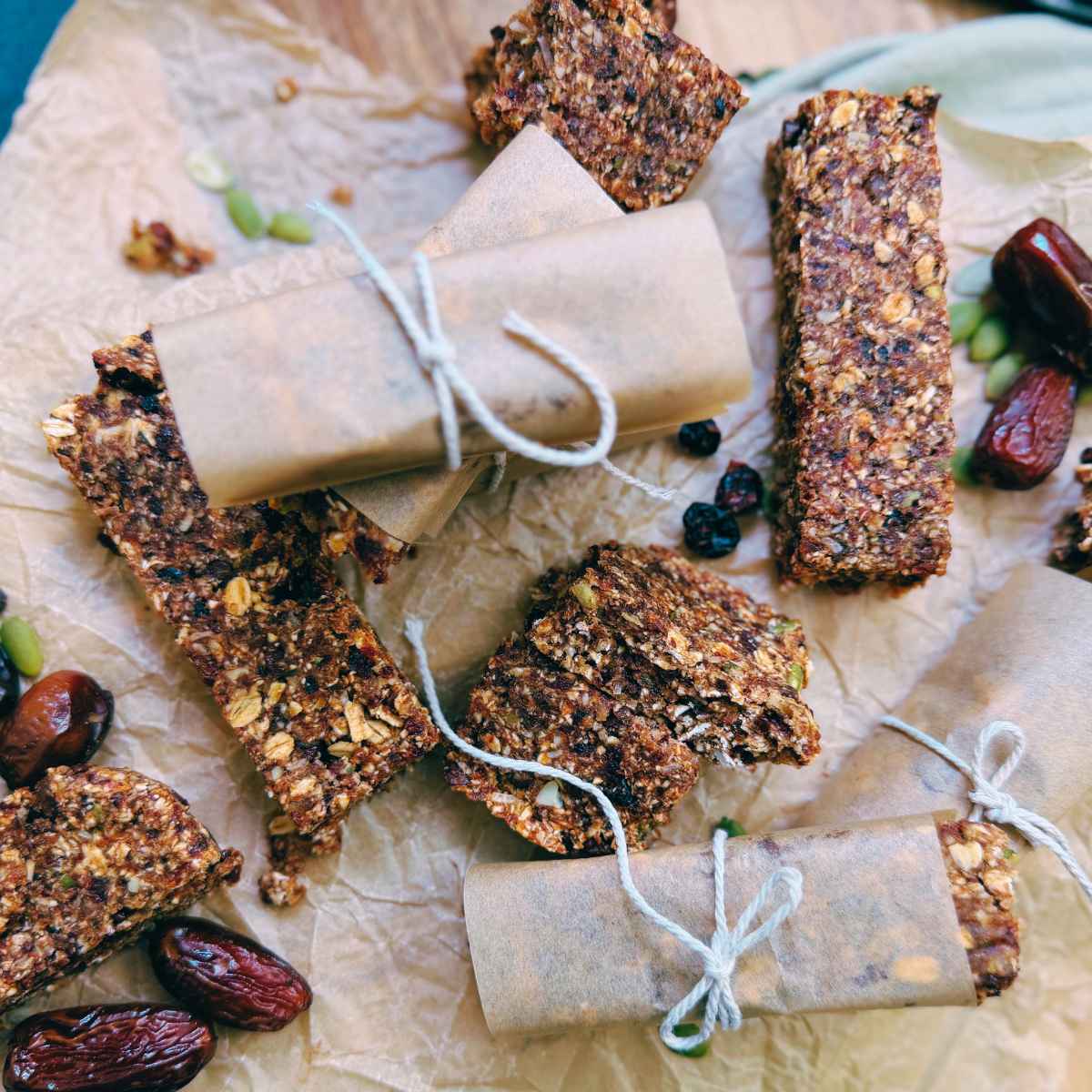 A collection of homemade granola bars. Some are wrapped in parchment paper.