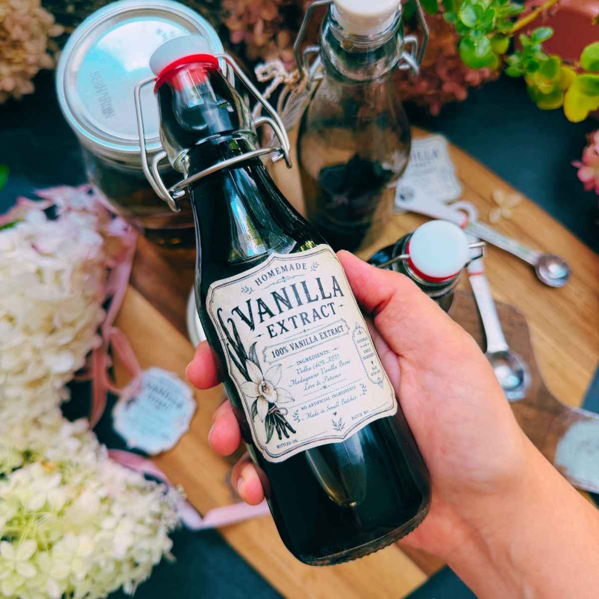 A woman is holding up a bottle of homemade vanilla extract.