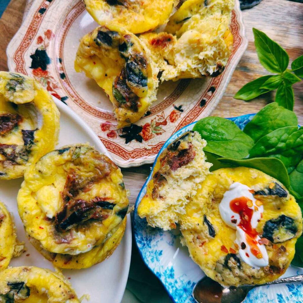 Tomato basil frittatas on three plates. There is spinach on the side.