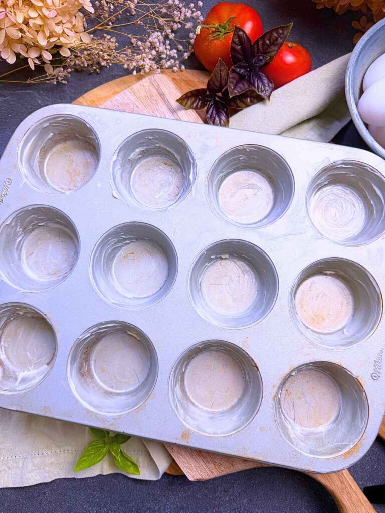 A metal muffin tin greased with butter.