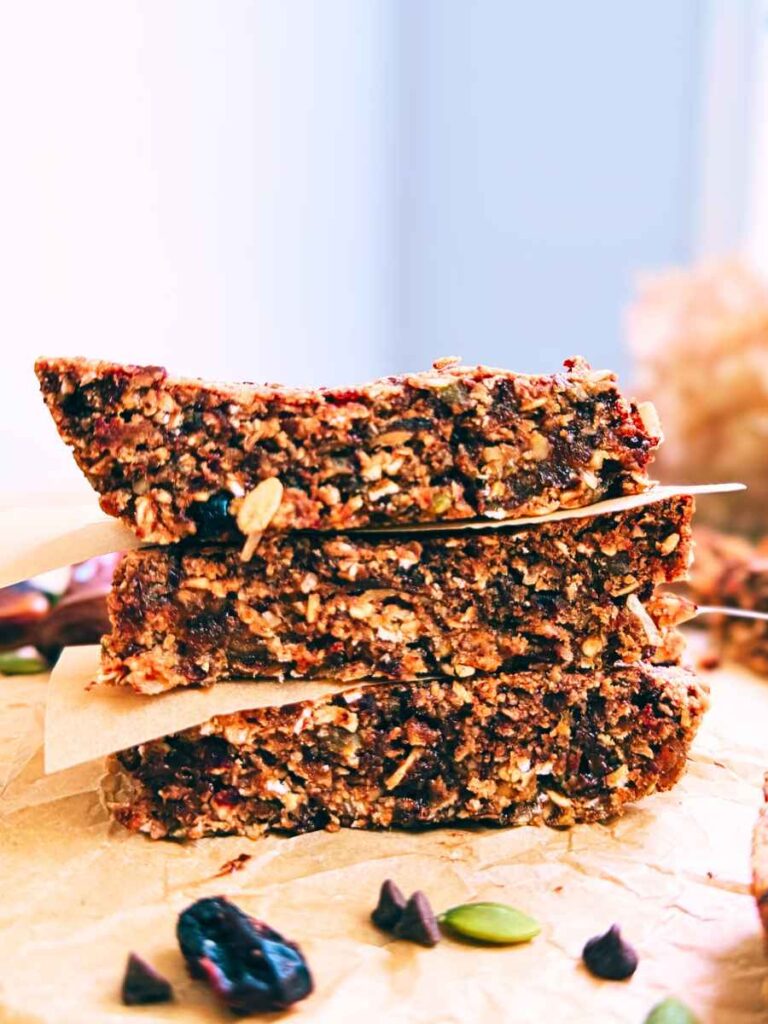 A stack of three homemade granola bars. There are pieces of parchment paper between them.