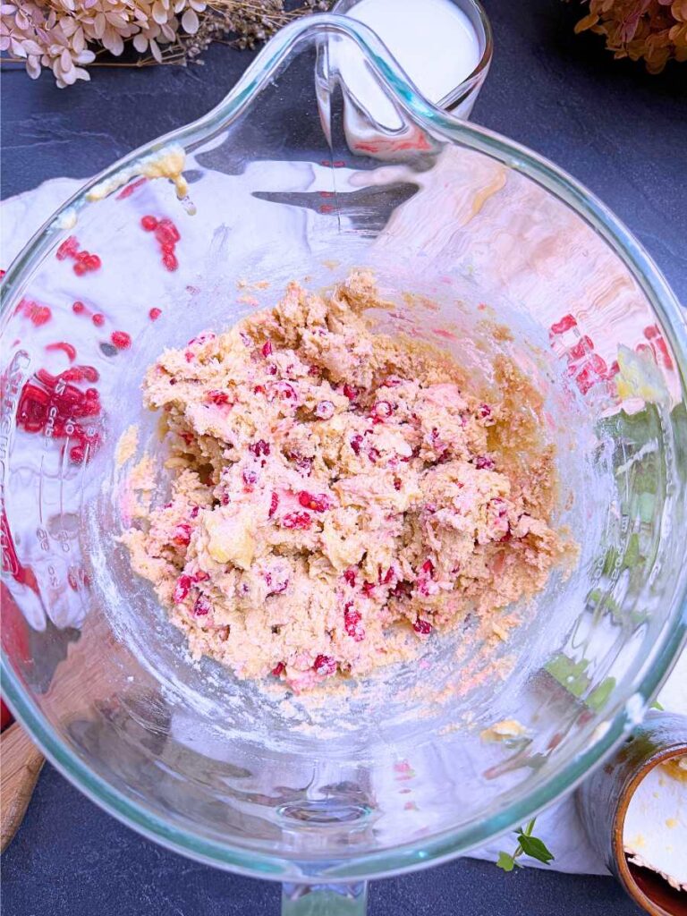 Red current cake batter in a glass measuring cup.