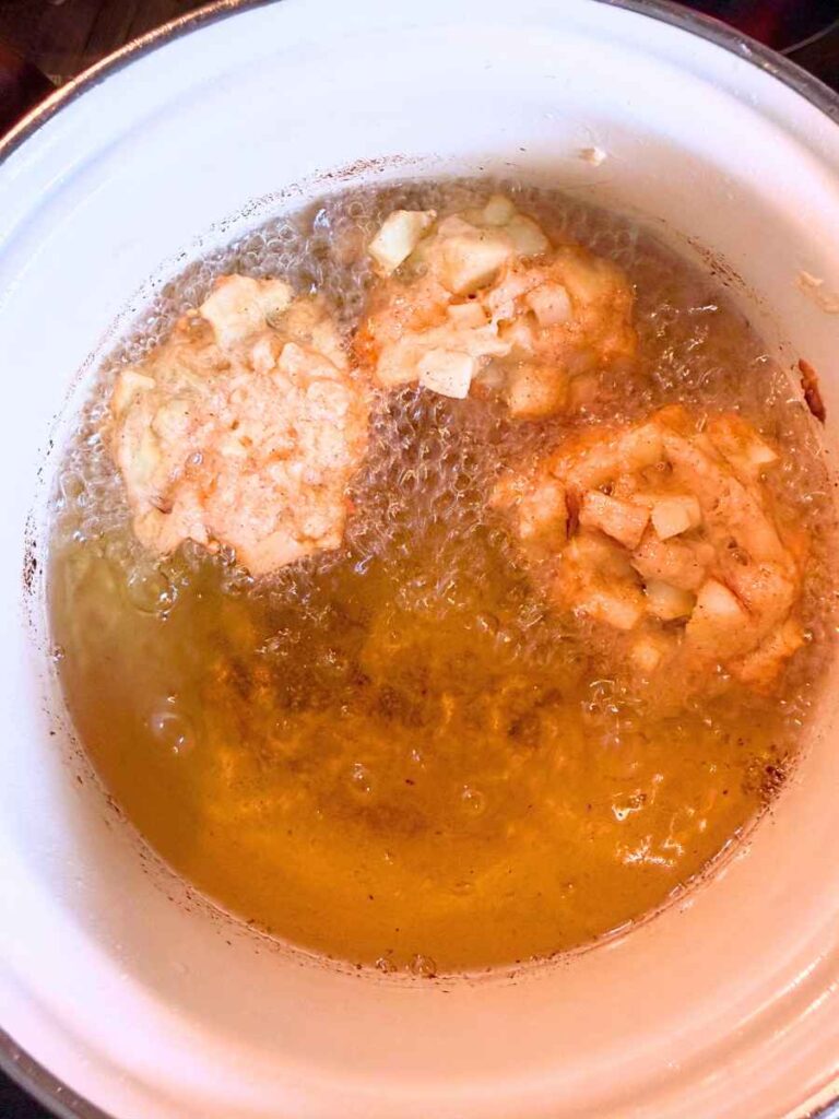 Apple fritter batter frying in hot oil.