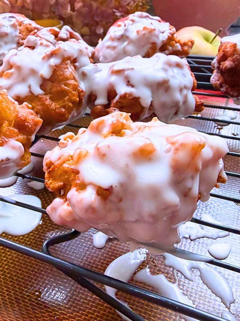 Glazed apple fritters on a wire rack.