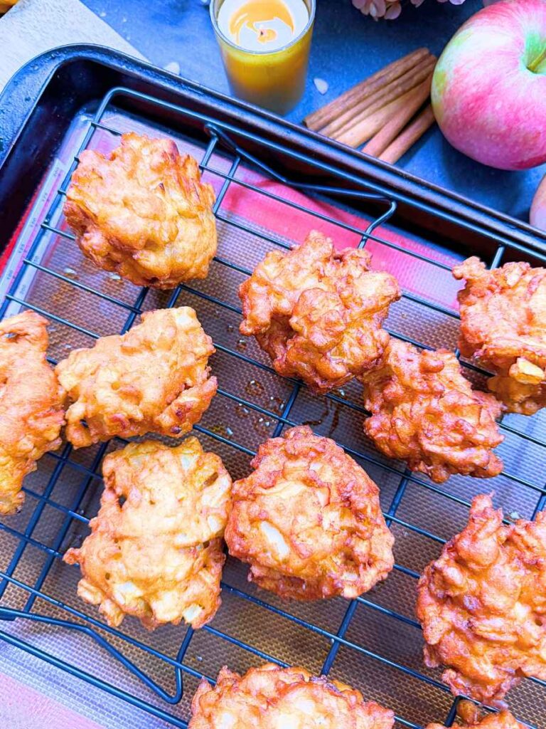 Cooked apple fritters on a wire rack.