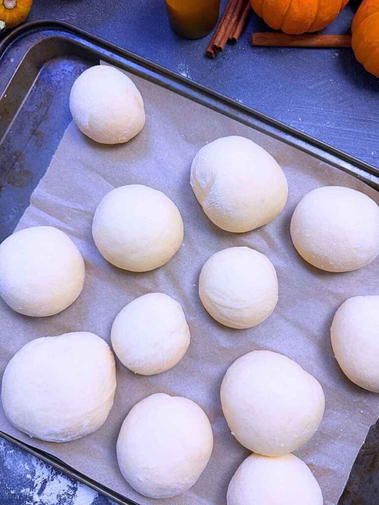 Risen brioche doughnut dough on a lined baking sheet.