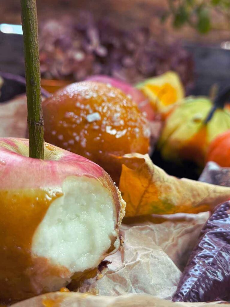A bitten candy apple on a piece of parchment paper. There are more in the background.
