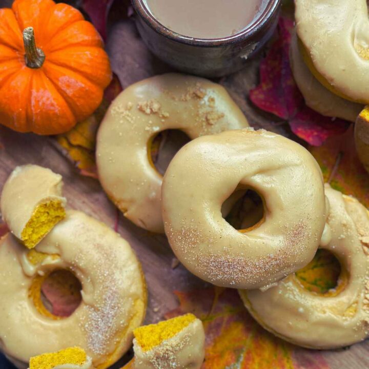 Three caramel iced pumpkin doughnuts There are more off to the side cut in half to show the inside colour.