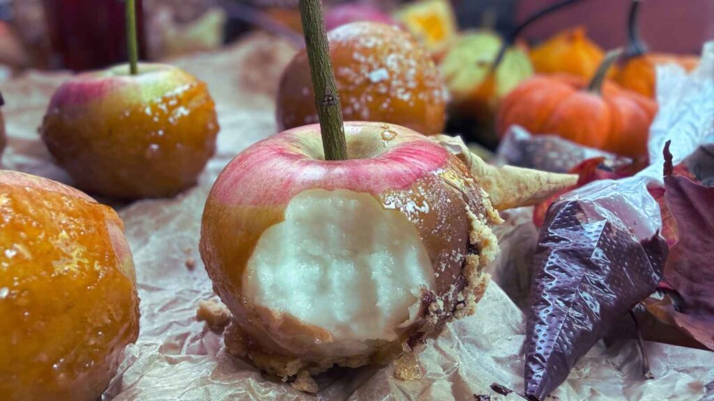 A maple dipped candy apple with a stick inside. It has a bite out of it.