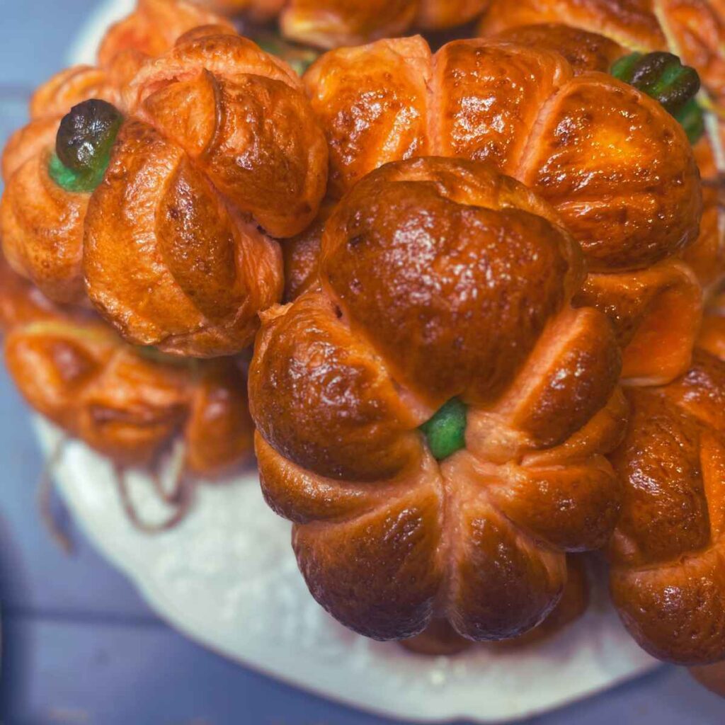 Bagels in the shape of pumpkins. They are orange and green.