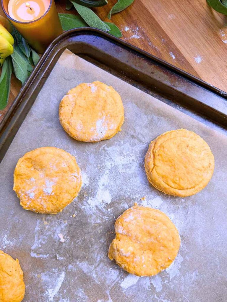 Unbaked pumpkin biscuits on a parchment lined baking sheet.