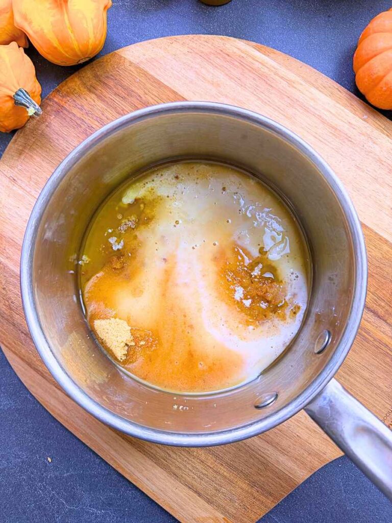 A metal sauce pot with butter, milk, and brown sugar inside.