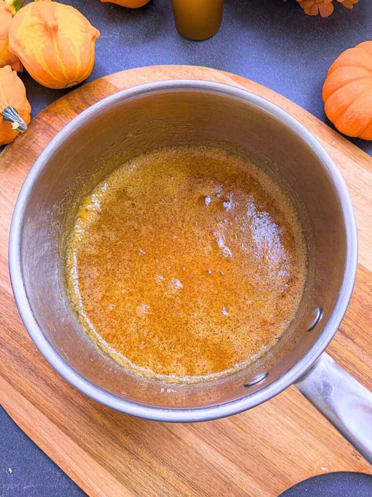 Cooked caramel sauce in a metal sauce pot.