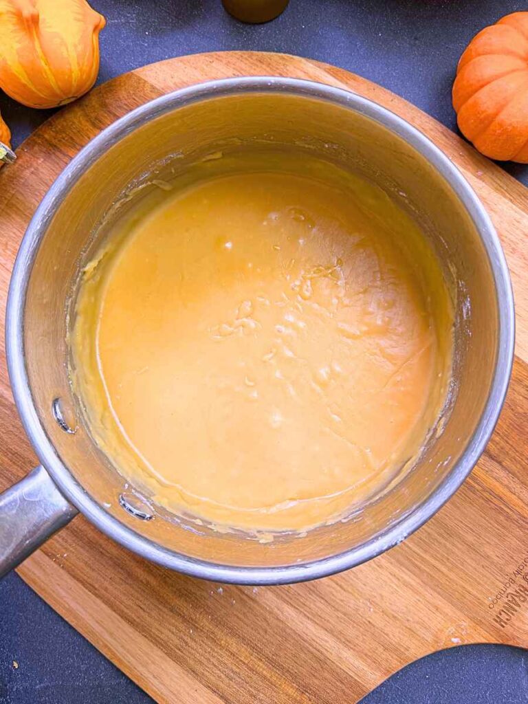 Cooked caramel icing in a metal sauce pot.
