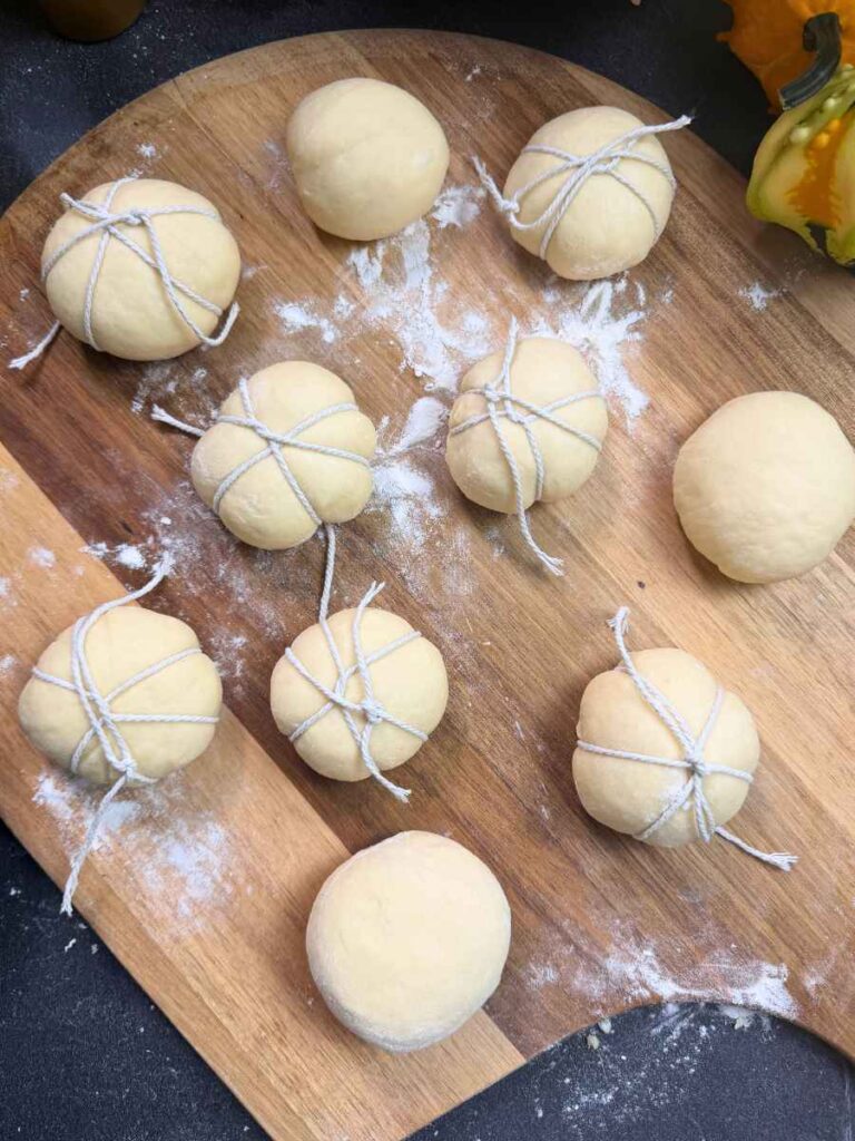 Twelve rolls of bread dough wrapped with kitchen twine.