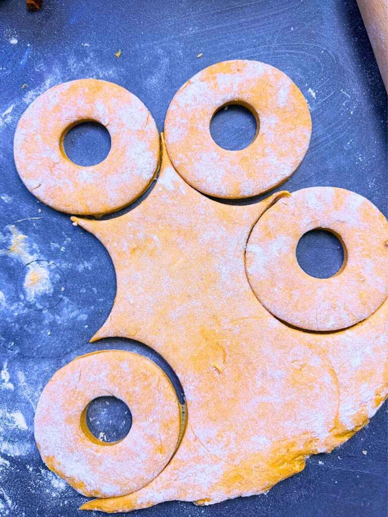 A rolled pumpkin doughnut dough cut into doughnut shapes.