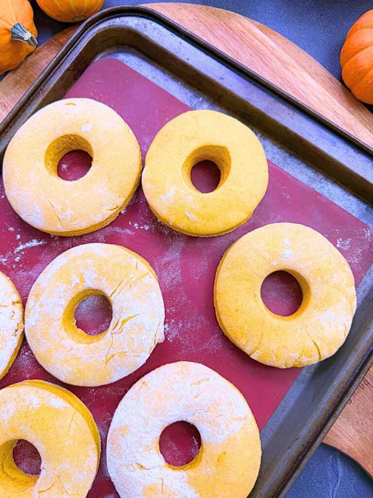 Baked pumpkin doughnuts on a lined baking sheet.