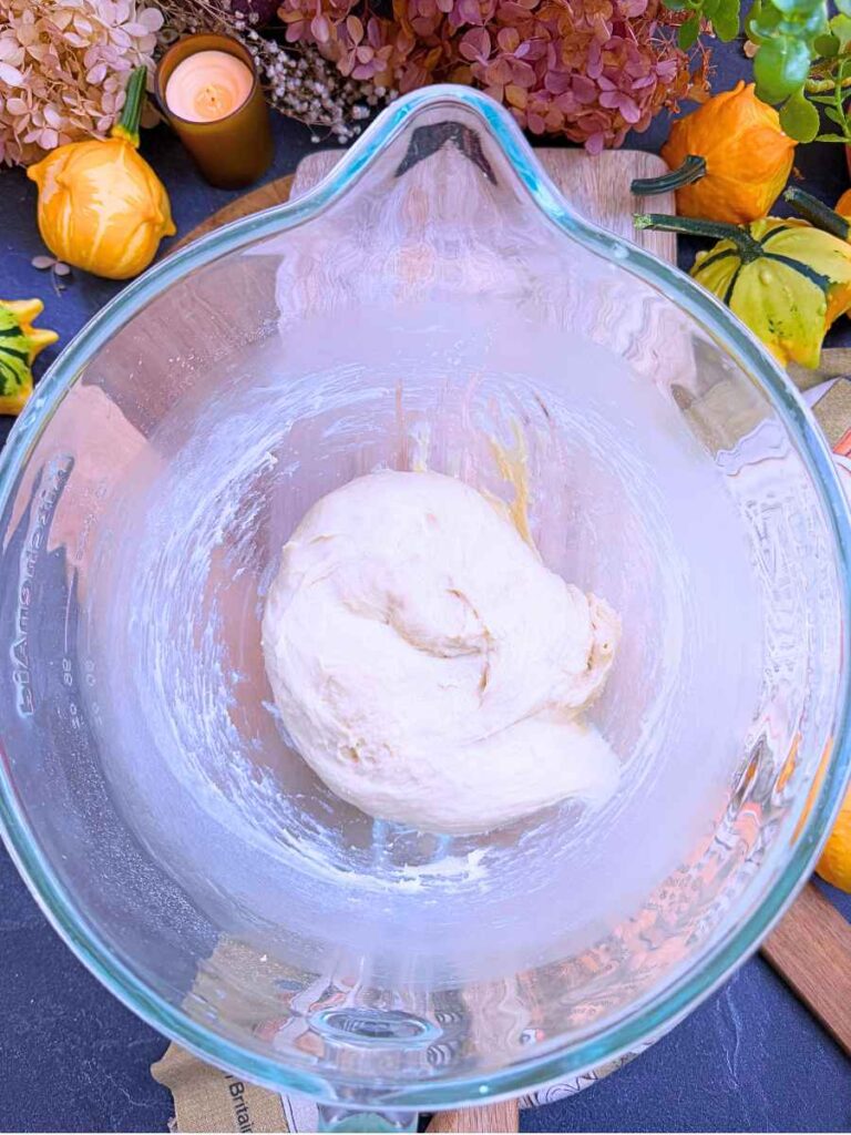 A large glass bowl with kneaded bread dough.