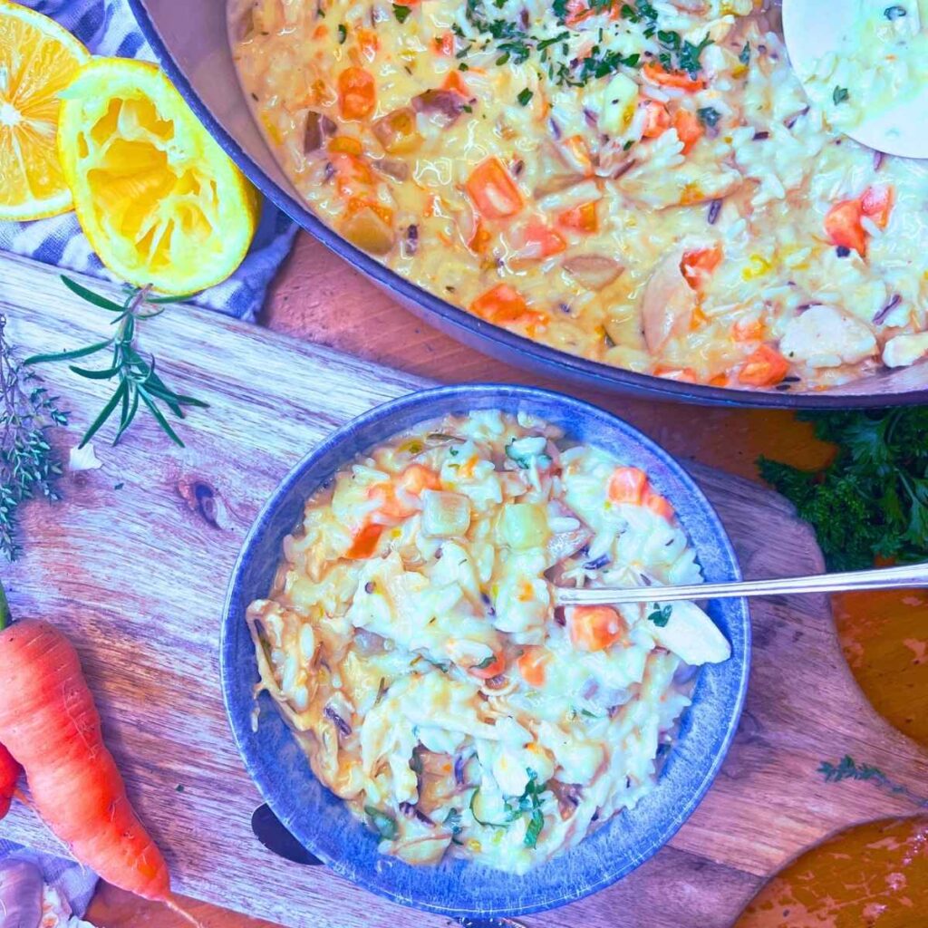 A blue bowl filled with turkey and rice soup. There is more in a sauce pot in the background.
