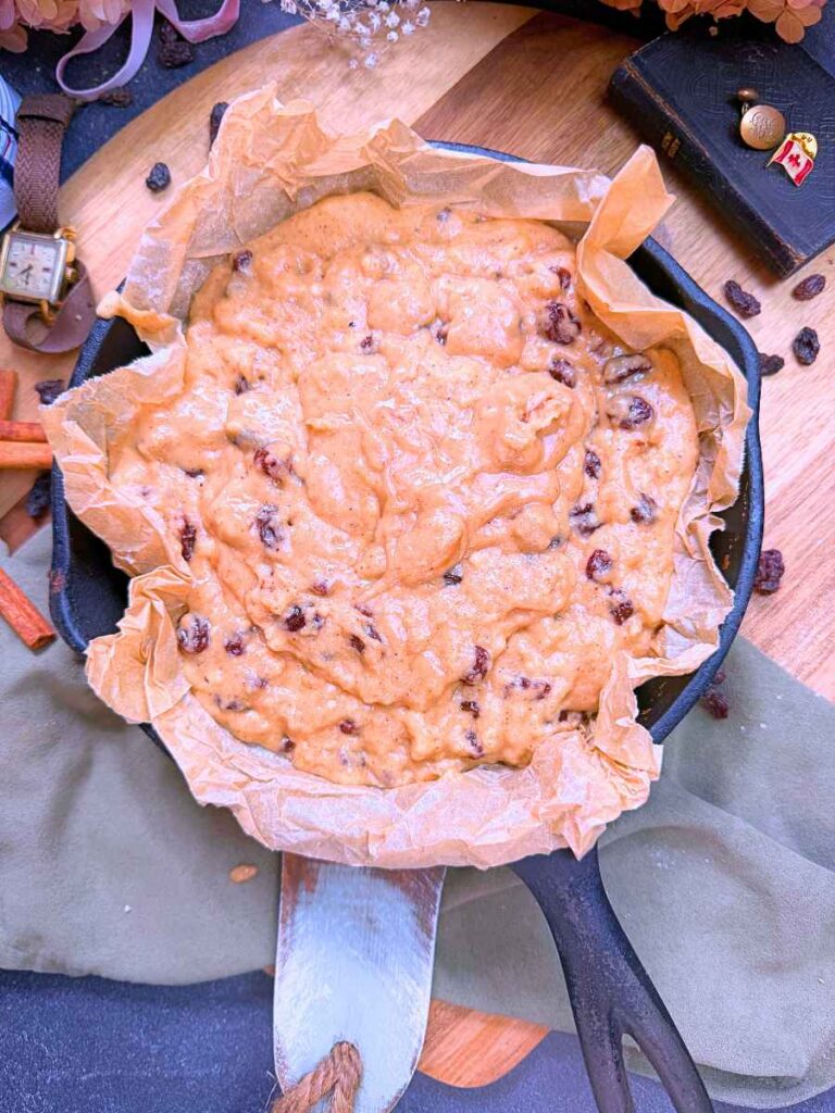 Canadian war cake batter in a parchment lined cast iron skillet.