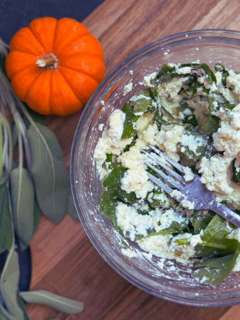 A bowl with ricotta cheese and spinach.