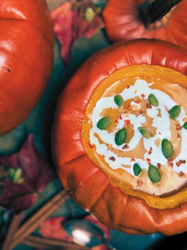 An overhead view of a cooked pumpkin with pumpkin soup inside.